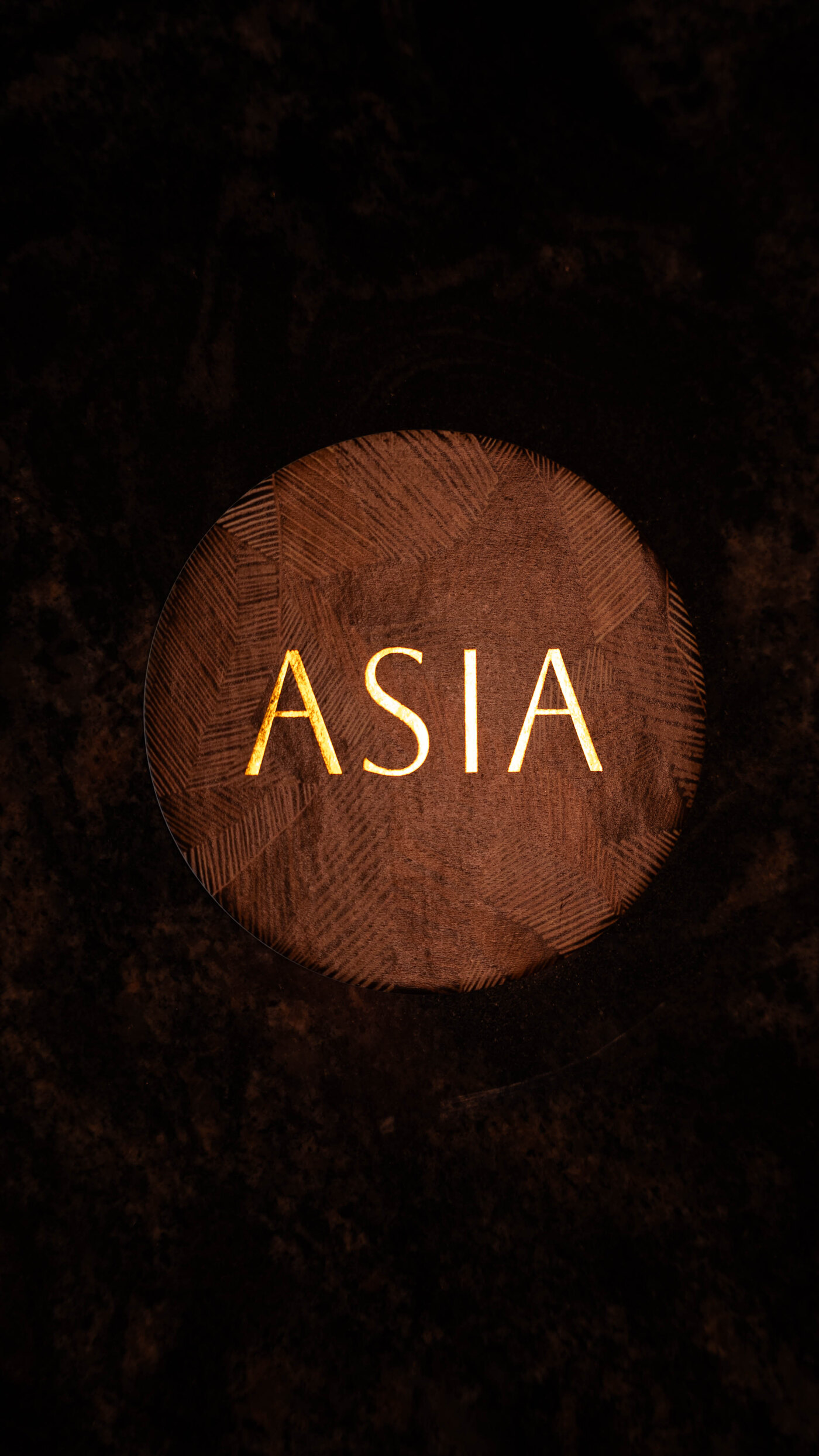 ASIA — the logo lit on an engraved wooden disc