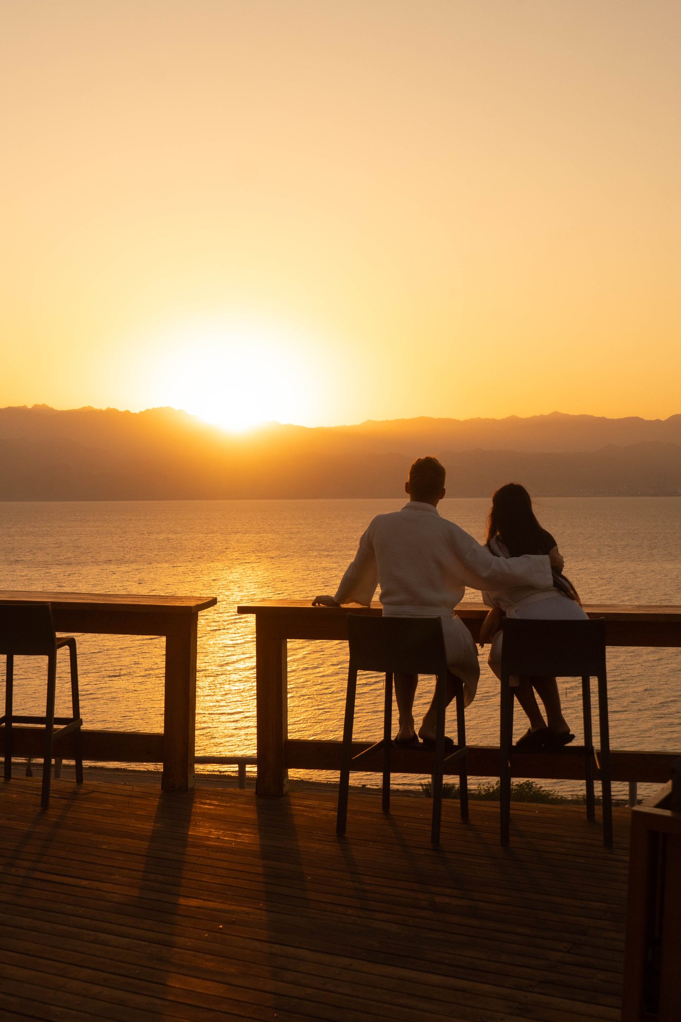 Two guests at a table as the sun goes down over the water