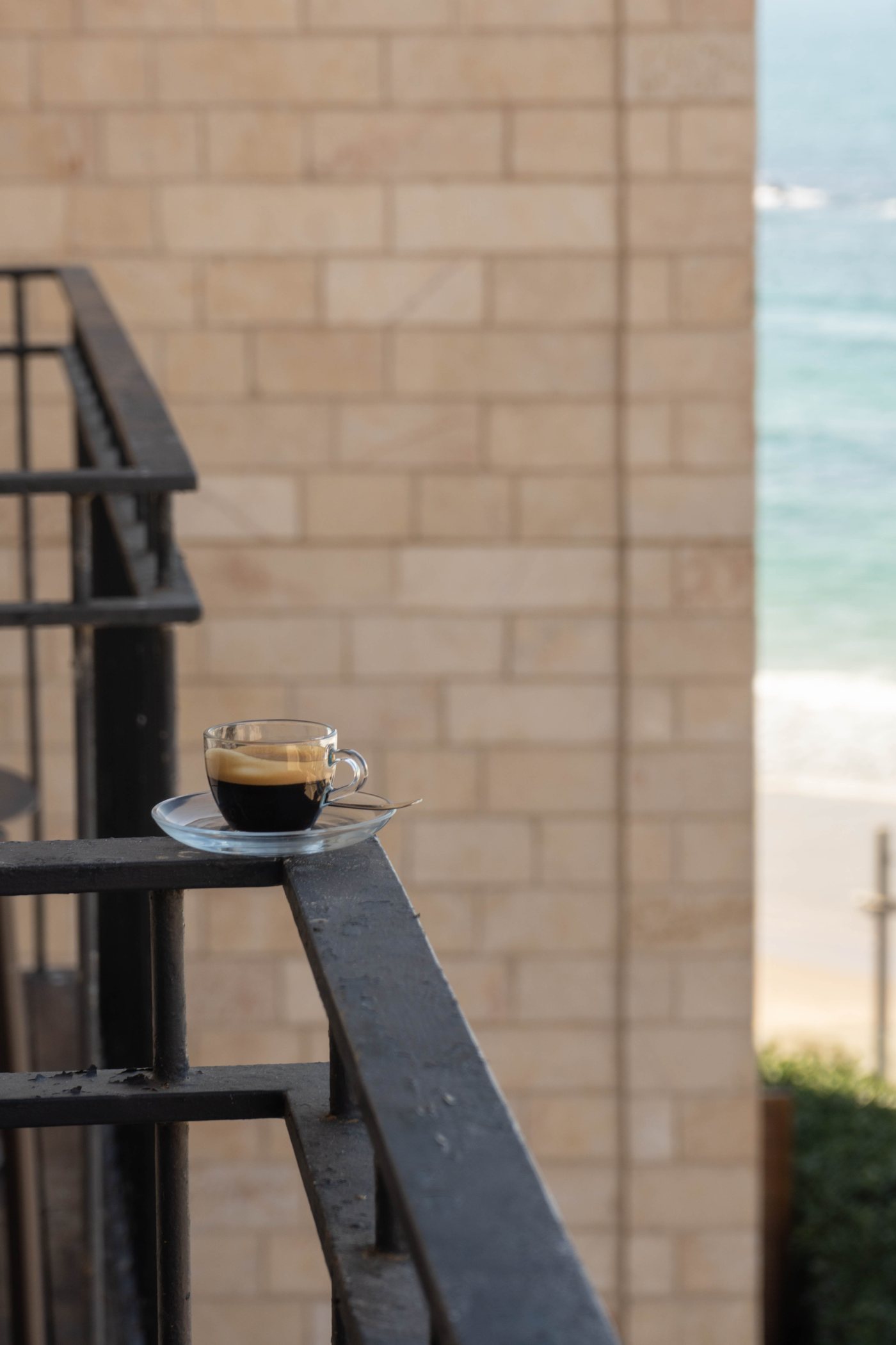 An espresso on the balcony rail, the sea beyond