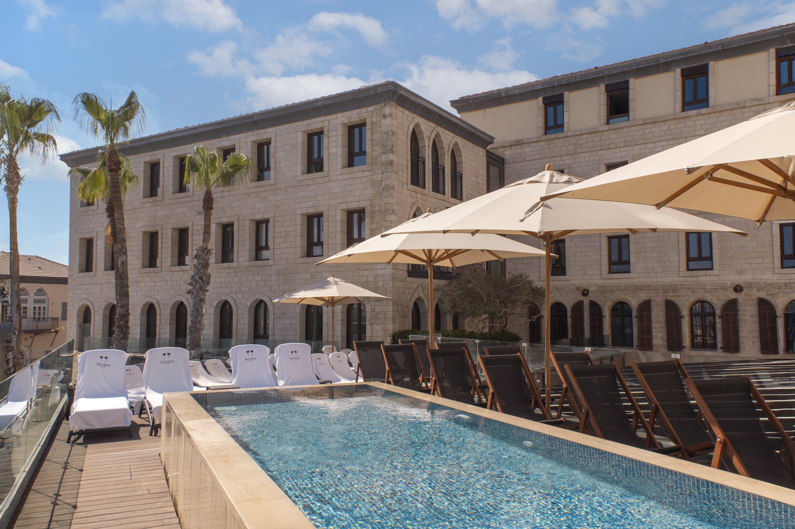 The pool, the historic building and the parasols above the sea