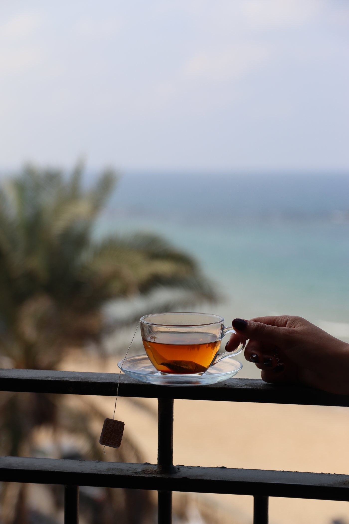 A glass of tea on the balcony rail, the sea behind