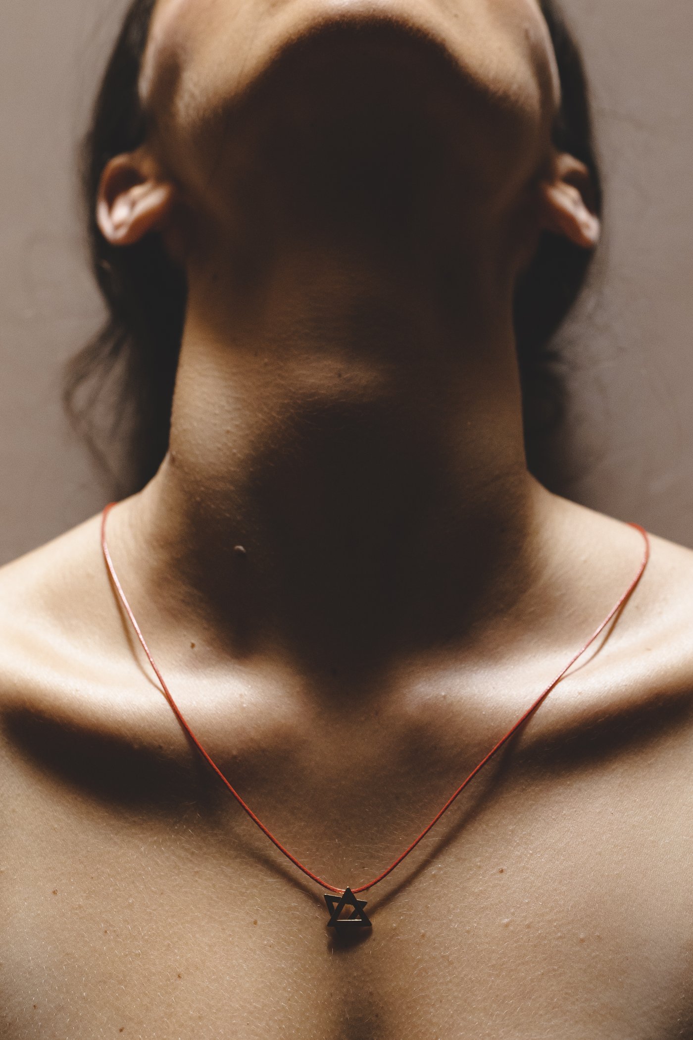 The cord at the throat, in shadow